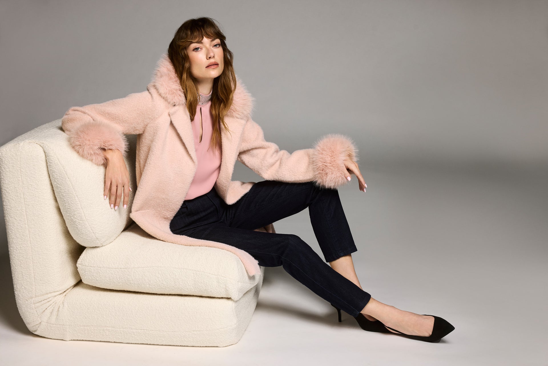 Rosa Teddyjacke mit weichem Finish, kombiniert mit pinkem Pullover und dunkler Hose – entspannter Lounge-Look im Studio