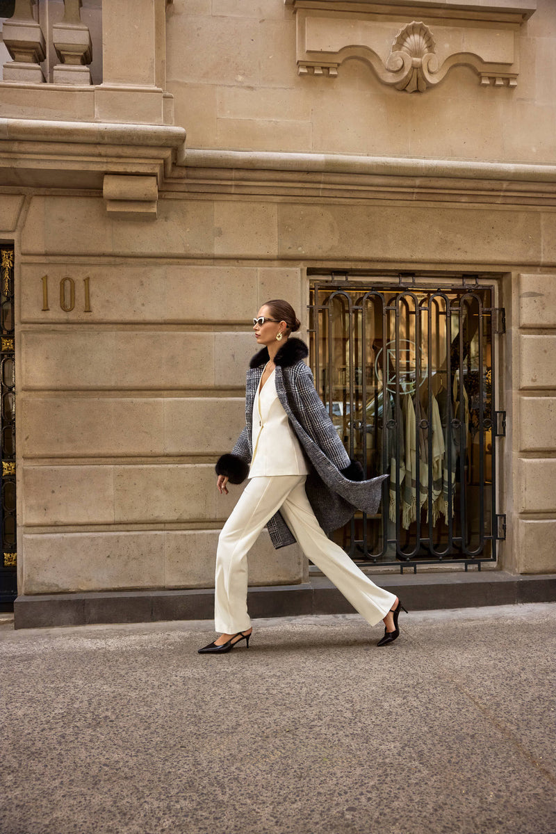 Weißer Hosenanzug in Bewegung – moderner Business-Look kombiniert mit grauem Mantel